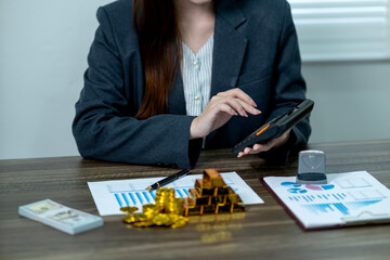 Asian adult businesswoman calculates investment portfolio financial growth wealth management strategy using calculator gold cash documents office workplace professional finance accounting