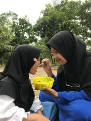 Mom Feeding Her Daughter Outside in a Natural Environment