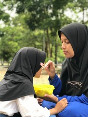 Muslim Mom Feeding Her Little Daughter Outside