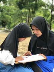 Hijabi Mom Guiding Her Little Girl to Study Outside