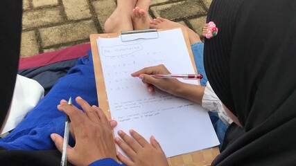 Mom Guiding Daughter Through Math Homework Outdoors