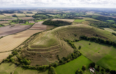 E over Hambledon Hill Iron Age hillfort. Neolithic long barrow visible on central ridge. Causewayed enclosure outside furthest rampart at 2 o&rsquo;clock