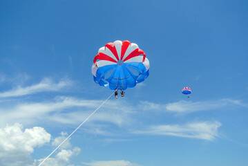Parasailing Adventure: Red, White, and Blue Parachute Against the Clear Sky