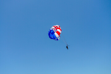 Parasailing Adventure: Red, White, and Blue Parachute Against the Clear Sky