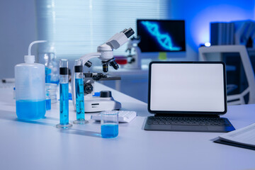 Modern laboratory showing analyzing equipment, tablet with blank screen, beakers and test tubes with blue chemical liquid