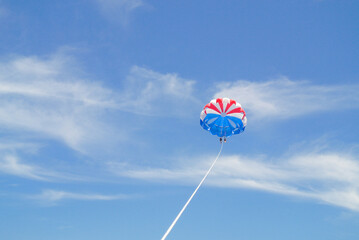 Parasailing Adventure: Red, White, and Blue Parachute Against the Clear Sky