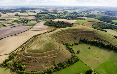 E over Hambledon Hill Iron Age hillfort. Neolithic long barrow visible on central ridge. Causewayed enclosure outside furthest rampart at 2 o&rsquo;clock