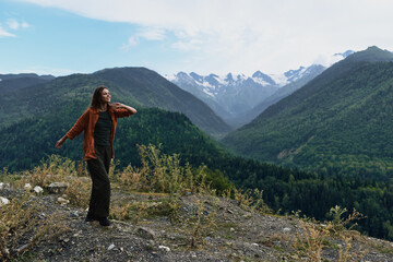 A hiker stands on a rocky outcrop overlooking a vast mountain landscape, soaking in the fresh air and dramatic valley below, conveying adventure and solitude in wild nature