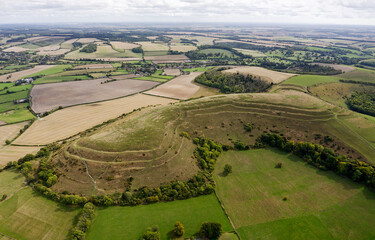 E over Hambledon Hill Iron Age hillfort. Neolithic long barrow visible on central ridge. Causewayed enclosure outside furthest rampart at 2 o&rsquo;clock