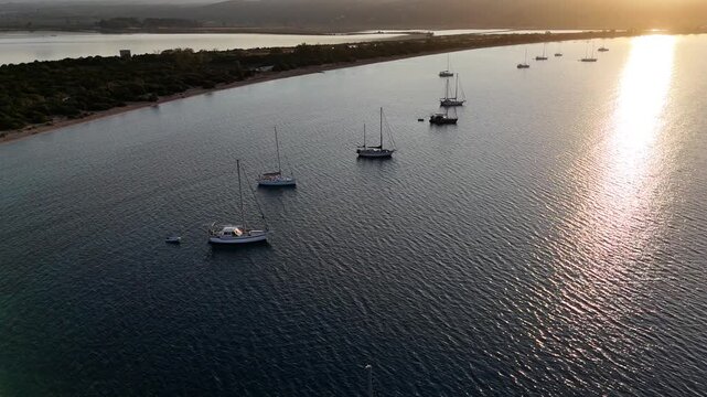 Navarin,Messinia,Gialoval Beach,Aerial forward towards the sun along the Gialova Beach and Lagoon.Lot of sailboats on anchor at the calm bay during sunset