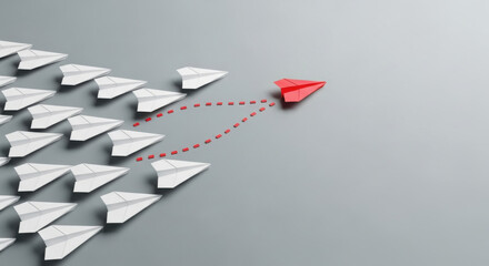 A red paper airplane leads a group of white paper planes on a gray backdrop, symbolizing leadership and innovative strategic direction.