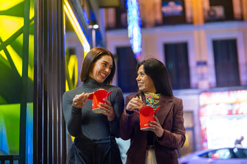 Friends enjoying takeaway noodles at city night