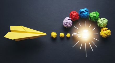 A yellow paper airplane leads towards a glowing light bulb surrounded by colorful crumpled paper balls on a dark gray backdrop, symbolizing idea generation and creative solutions.