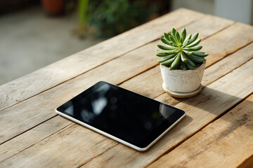 木製のデスクに置かれた多肉植物と黒い画面のタブレット