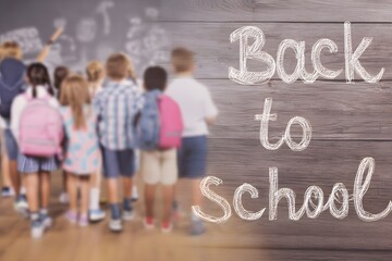 Children with backpacks walking towards a chalkboard with the words back to school written on it