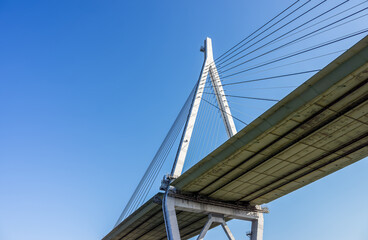 Obraz premium Tempozan Bridge Pylon and Cables Against Blue Sky with Copy Space. Worm's-eye view of the massive pylon and tensioned cables of the Tempozan cable-stayed bridge in Osaka, Japan.