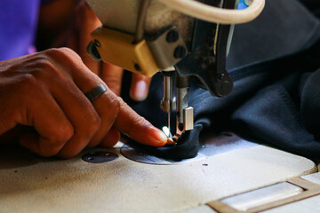 A sewing machine and the hand of a tailor working on a sewing machine