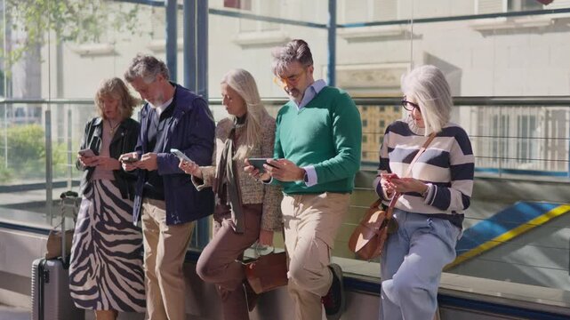 Stylish senior friends using smartphones together outdoors