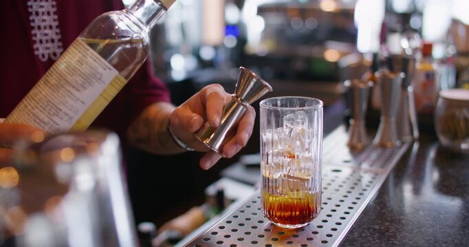 Mixologist work. Making cocktail. Bartender pouring sweet aroma color syrup from metal jigger to glass. Flavored refreshing drink.