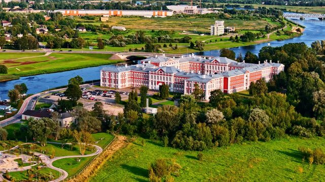 Jelgava Palace in Latvia captured from air, surrounded by Lielupe river with golden hour sunlight