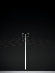 A stark, minimalist composition features a tall, slender pole with overhead wires against a dark backdrop