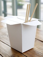 A white take-out food container with chopsticks on a wooden table near a window