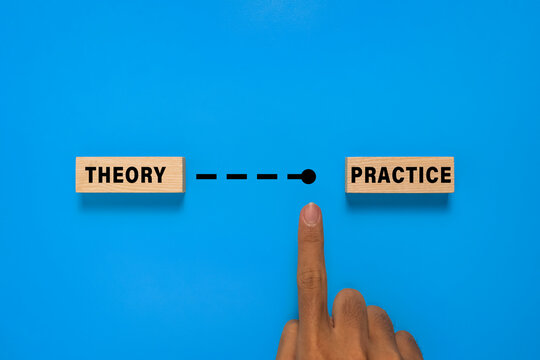 male hand point wooden blocks with theory and practice words. isolated on blue background. concept of implementing theory to practice