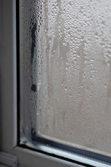 Water droplets collect on a window surface, showing high humidity. Proper ventilation is necessary to reduce dampness inside homes. This helps in fighting mold and fungi effectively.
