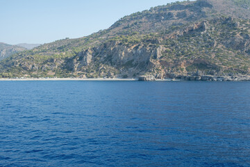 Rocky coastline and deep blue sea at Sougia beach upon the southern coast of Crete, Greece, sunny summer day, blue sky