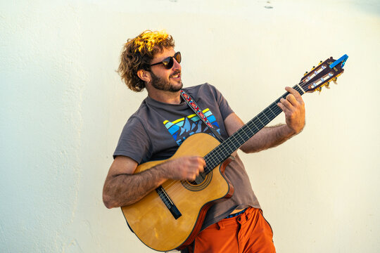 Man playing acoustic guitar smiling outdoors at sunset