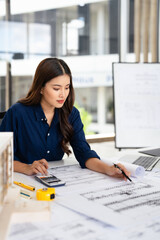 Civil Engineer working on shop drawings of  post tension slab plan on desk with Calculator and...