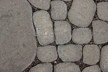 Obraz premium Textured stone pavement composed of various shapes and sizes, showcasing a natural arrangement of gray stones with earthy tones, ideal for outdoor pathways and landscaping design