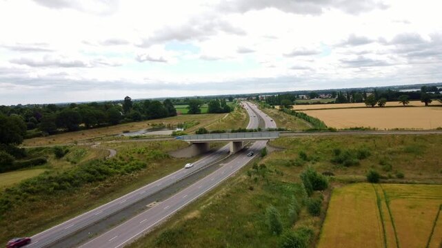 Aerial footage over Middle Road bridge over the NDR in Norfolk. Cars and other vehicles driving in each carriage way. Drone footages moves forward, slowly over the bridge.