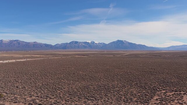 The view rises from inside the Rio Grande Gorge, revealing the vast Taos Plateau and the towering Sangre de Cristo Mountains in Northern New Mexico.