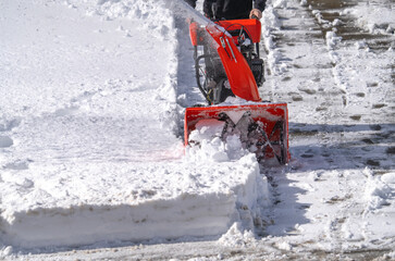 man removing snow on the driveway of the house by snow blower