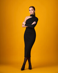 Full-length fashion portrait: woman in a fitted black one-shoulder midi-dress, posing confidently against a vibrant orange background. Chic, high-contrast, modern.