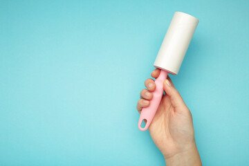 Woman holding lint roller on blue background. Top view
