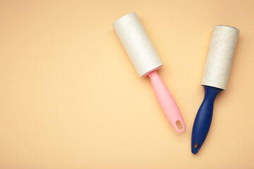 Cloth fabrics cleaner lint roller brush with paper roll on beige background. Sticky roller, pet cat dog fur dust hair remover