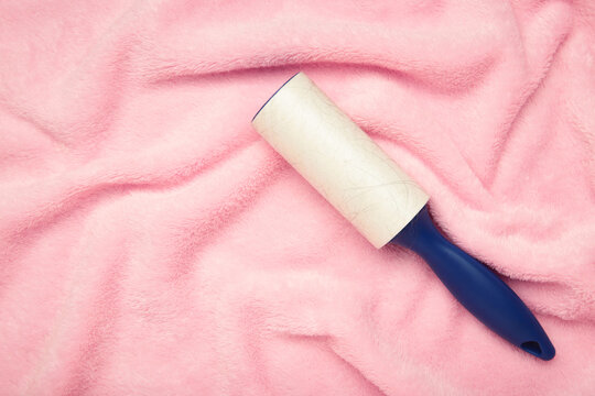 Lint roller on pink texture background to remove pet animal hair.