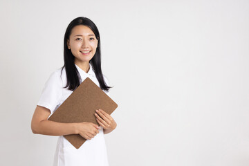 Smiling woman in white coat holding clipboard in hands