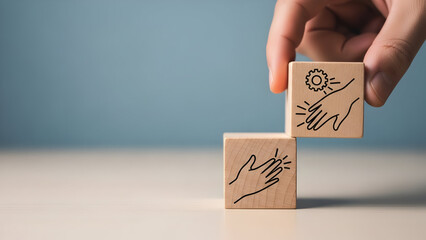 Hand stacking wooden blocks with icons representing cooperation and progress
