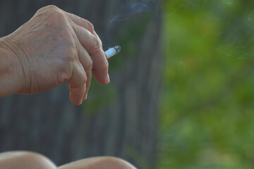 A smoldering cigarette in a woman's hand
