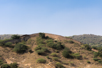 The extensive fortress wall of Amer or Amber fort located on Aravalli range of hills in Jaipur , Rajasthan