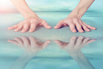 Hands touching reflective water surface with sparkles creating contemplative calm mood