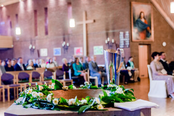 Baptismal font with flowers and pitcher during ceremony in brick-walled church interior