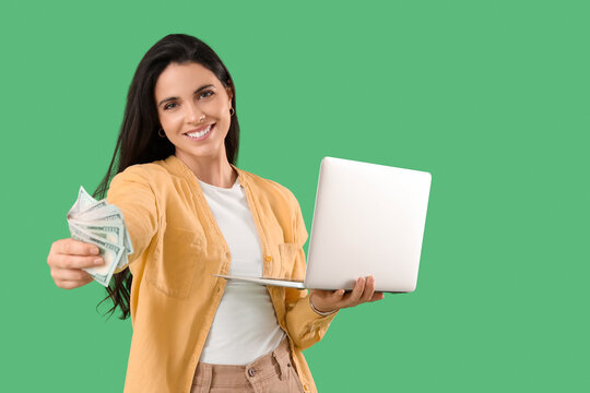 Happy young woman with laptop and money on green background. Sports bet concept