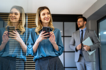 In a modern office, a successful businesswoman multitasks with phone communication
