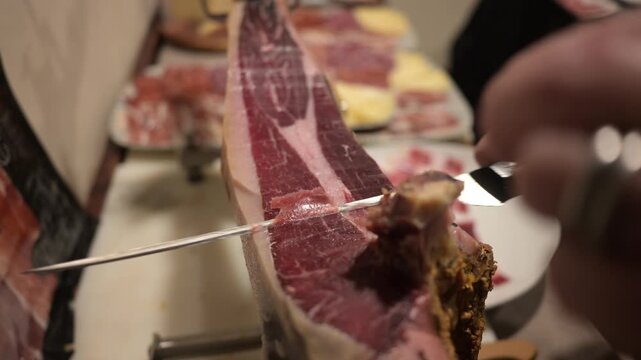 Person skillfully slicing spanish serrano ham
