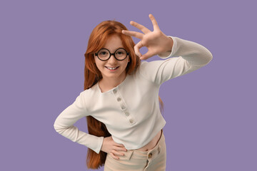Teenage redhead girl showing OK gesture on lilac background