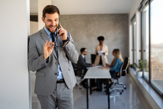 A confident business man leads her busy office life, multitasking with smartphone communication - Powered by Adobe